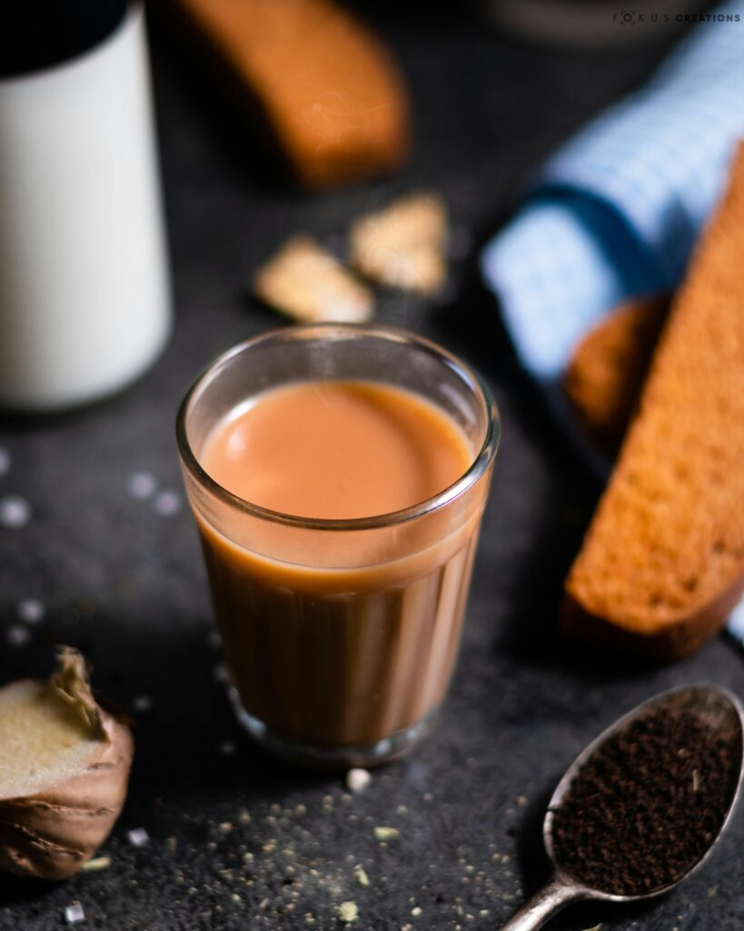 A glass of spiced chai with ginger and biscuits, perfect for a warm breakfast or snack.